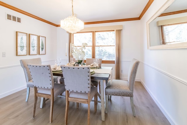 dining area with crown molding, wood finished floors, a healthy amount of sunlight, and visible vents