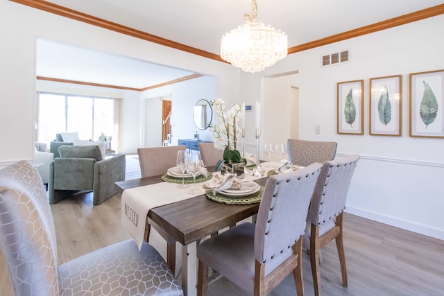 dining area featuring visible vents, ornamental molding, an inviting chandelier, light wood finished floors, and baseboards