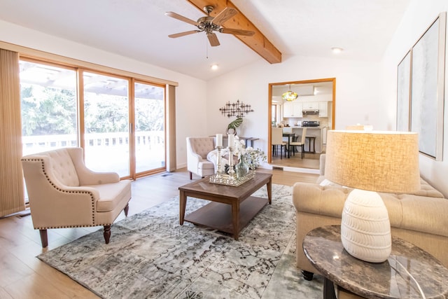 living area with a ceiling fan, vaulted ceiling with beams, and wood finished floors