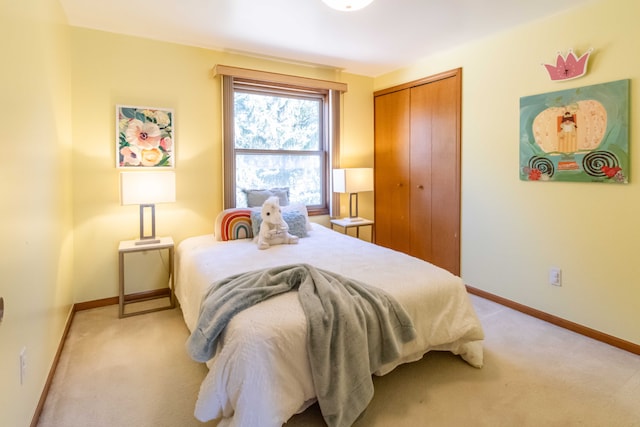 bedroom with a closet, light colored carpet, and baseboards