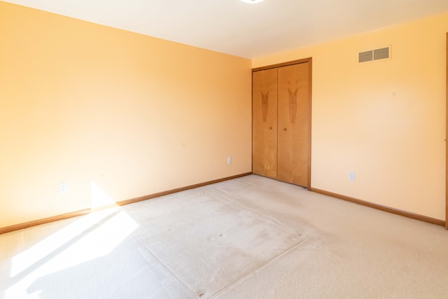 spare room featuring visible vents, baseboards, and light colored carpet