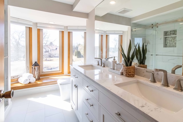 bathroom with double vanity, a stall shower, visible vents, and a sink