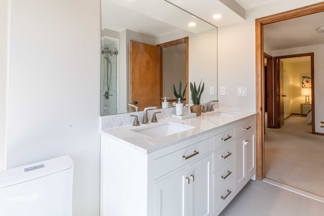 bathroom with toilet, double vanity, walk in shower, and a sink