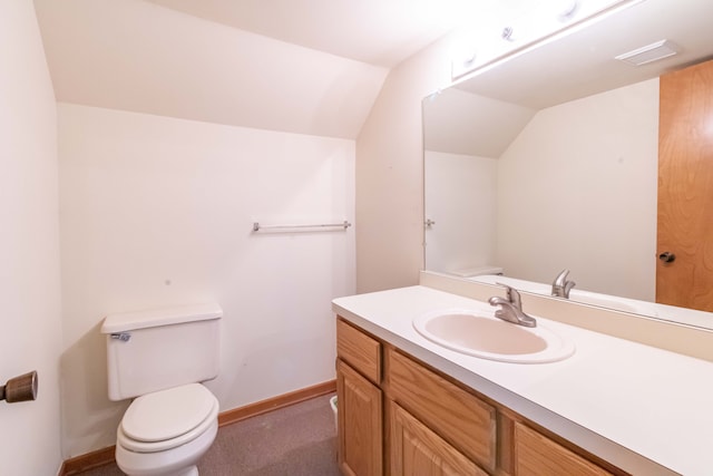 bathroom with baseboards, toilet, vanity, and vaulted ceiling