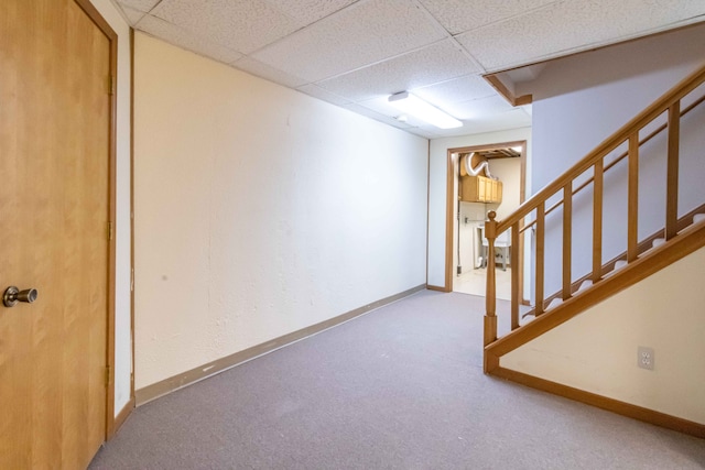 finished basement with baseboards, stairs, a paneled ceiling, and carpet floors