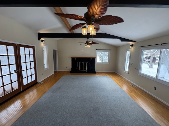 unfurnished living room featuring ceiling fan, light hardwood / wood-style flooring, lofted ceiling with beams, and french doors