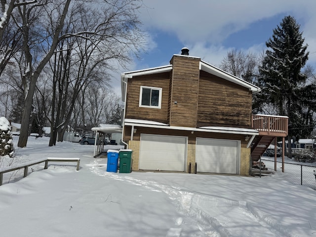 view of snowy exterior with a deck and a garage