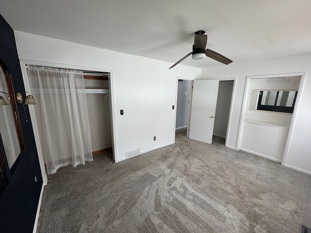 unfurnished bedroom featuring dark colored carpet, ceiling fan, and multiple closets