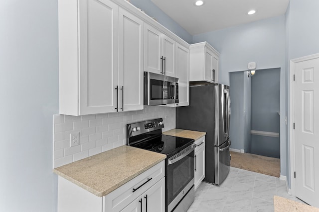 kitchen featuring backsplash, appliances with stainless steel finishes, and white cabinets