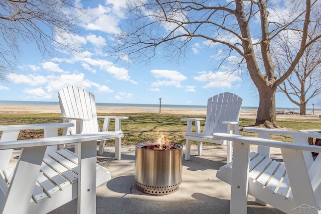 view of patio / terrace with a water view, a fire pit, and a beach view