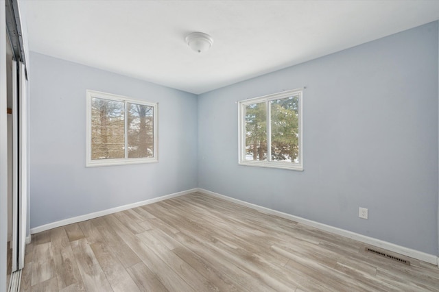 empty room featuring light wood-style floors, baseboards, and visible vents