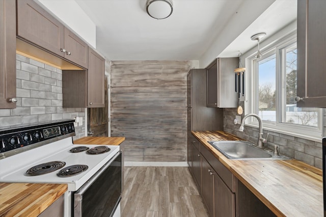 kitchen featuring hanging light fixtures, a sink, wooden counters, and white electric range