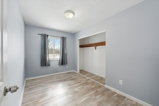 unfurnished bedroom with a closet, light wood-style flooring, and baseboards