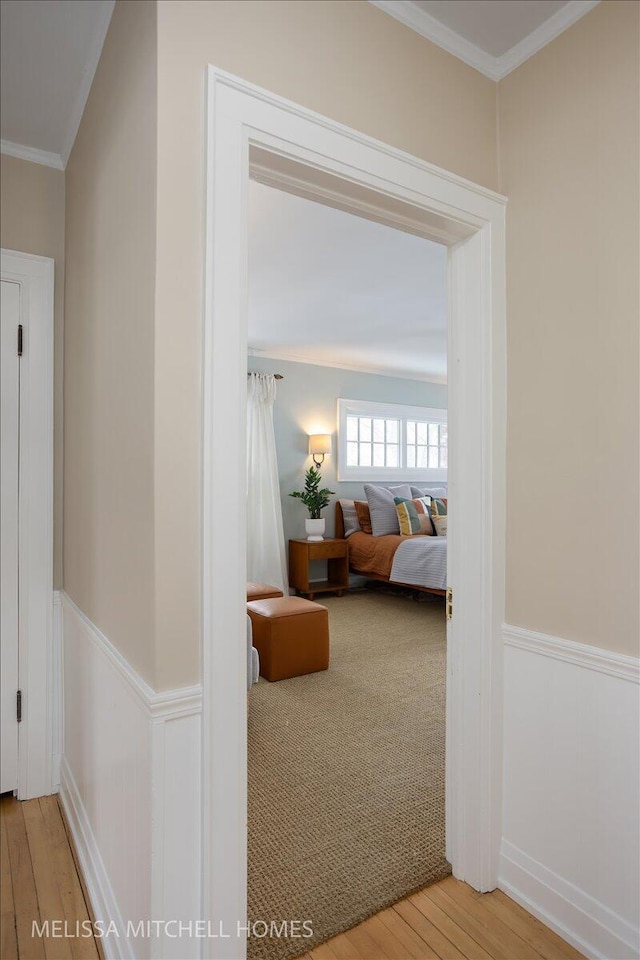 hallway featuring light wood-type flooring and ornamental molding