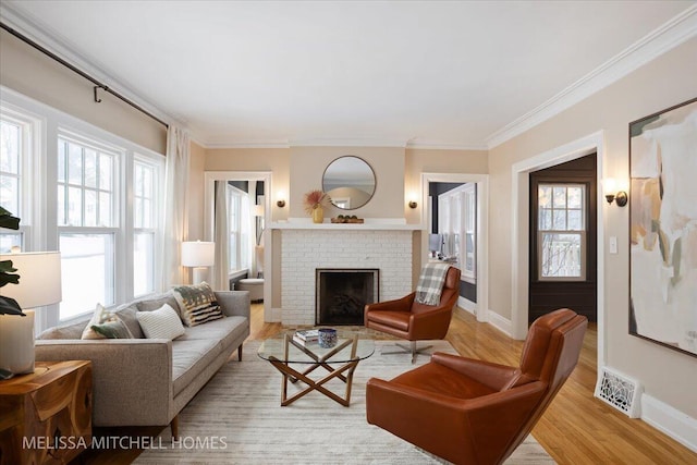 living room with ornamental molding, light wood-type flooring, and a brick fireplace