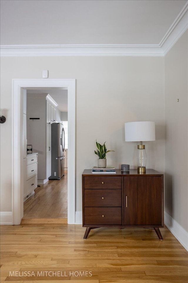 hallway with light hardwood / wood-style floors and ornamental molding