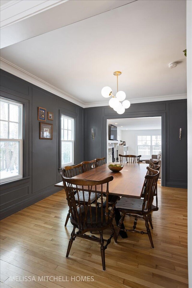 dining area with ornamental molding, light hardwood / wood-style floors, and an inviting chandelier