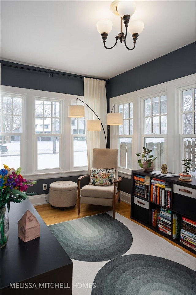 sitting room with a notable chandelier, plenty of natural light, and wood-type flooring