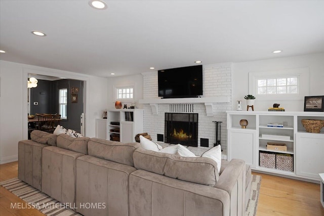 living room featuring light hardwood / wood-style flooring and a brick fireplace