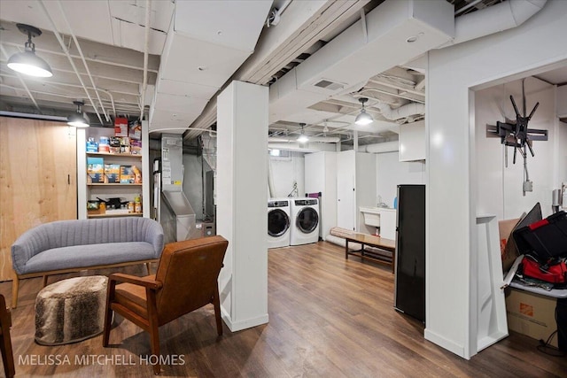 basement featuring sink, separate washer and dryer, heating unit, and wood-type flooring