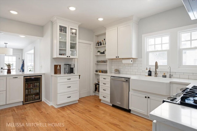 kitchen with white cabinets, stainless steel dishwasher, a wealth of natural light, beverage cooler, and sink