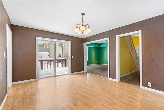 spare room featuring light wood-type flooring and a chandelier