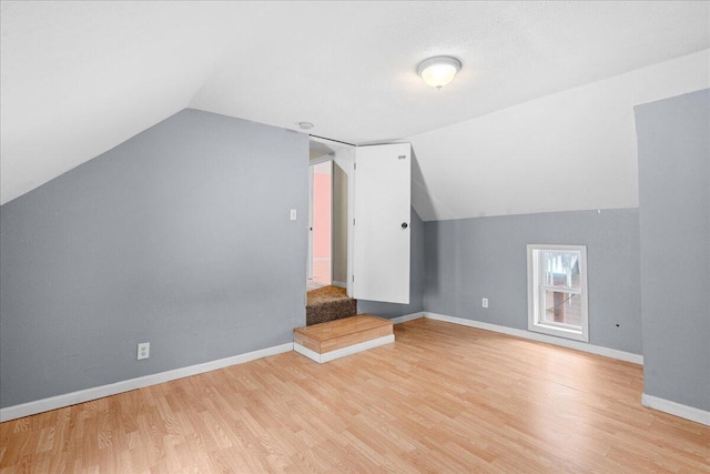 additional living space featuring light wood-type flooring and lofted ceiling