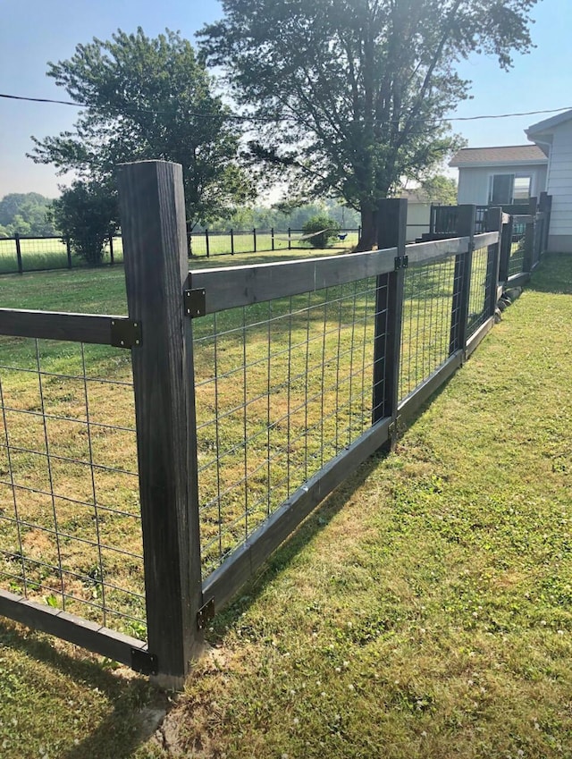 view of gate with a rural view, fence, and a yard