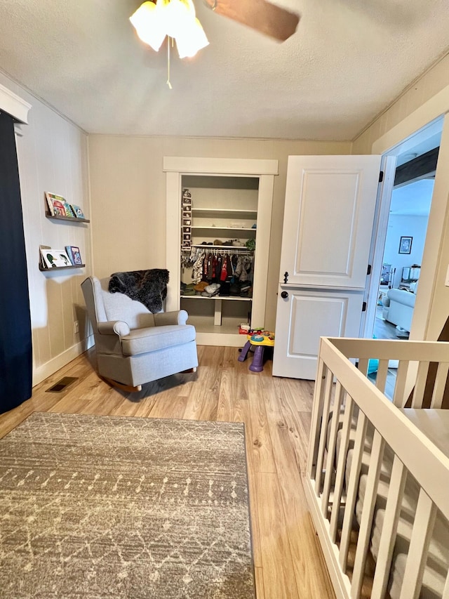 interior space with visible vents, ceiling fan, a textured ceiling, light wood-style floors, and a closet