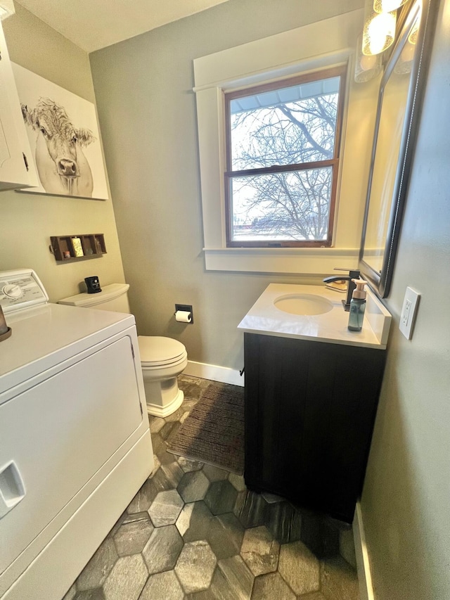 half bath featuring toilet, washer / clothes dryer, vanity, and baseboards