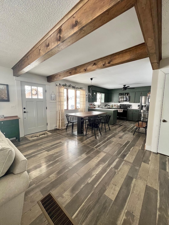 living area with dark wood-style floors, a textured ceiling, ceiling fan with notable chandelier, and beam ceiling