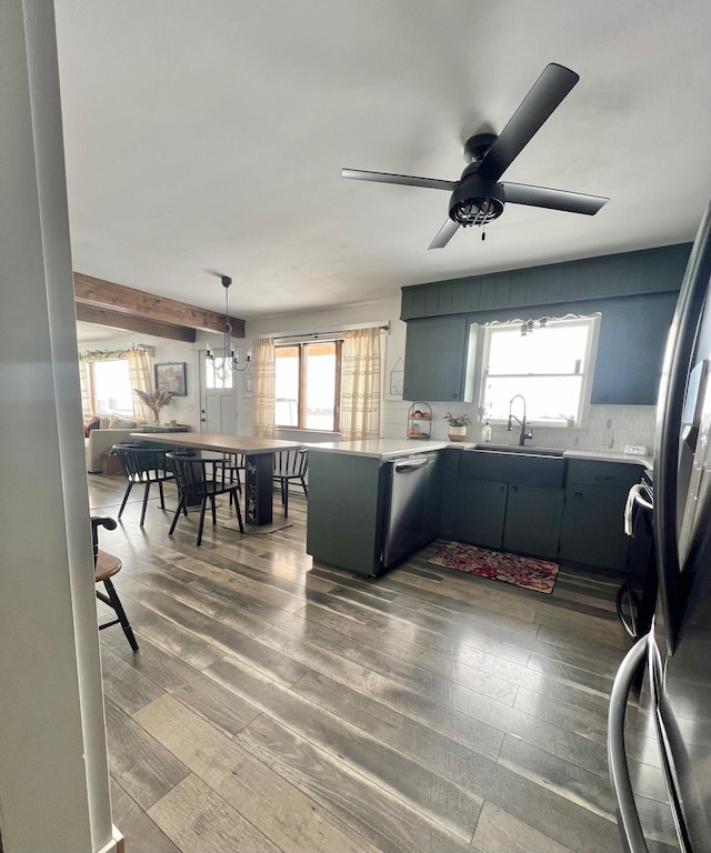 kitchen with stainless steel appliances, a sink, light countertops, a wealth of natural light, and dark wood finished floors