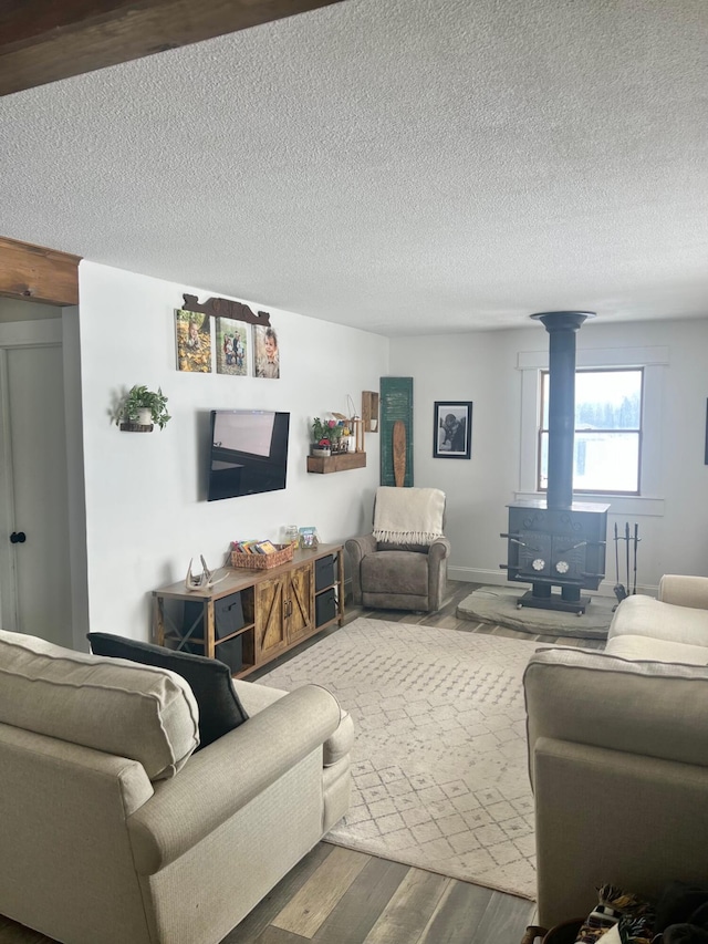 living area with a textured ceiling, wood finished floors, and a wood stove