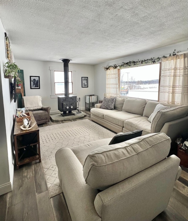 living area featuring a textured ceiling, wood finished floors, a wood stove, and baseboards