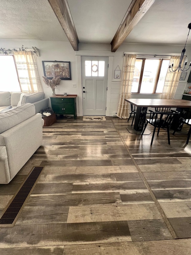 entryway with a wealth of natural light, dark wood-style flooring, and beamed ceiling