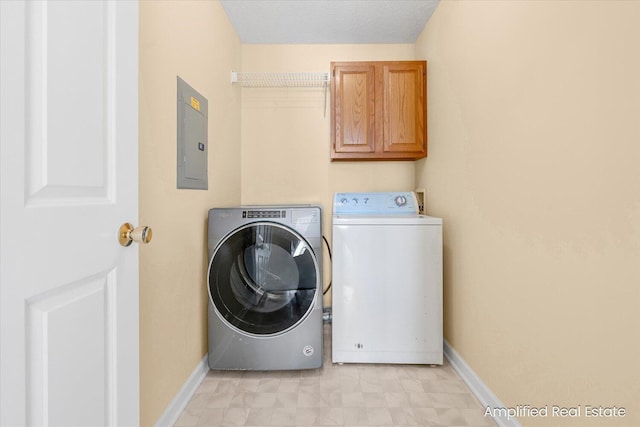 laundry area featuring electric panel, washer and clothes dryer, and cabinets