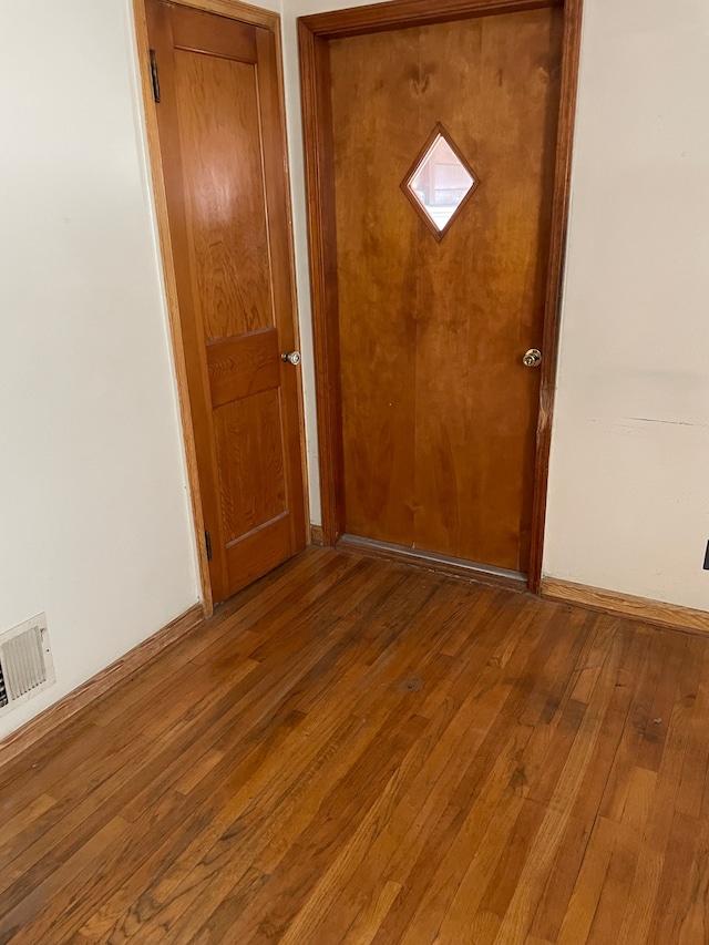 interior space with baseboards, wood finished floors, and visible vents