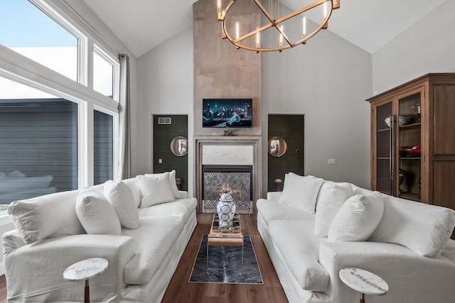 living area featuring a premium fireplace, high vaulted ceiling, a chandelier, and dark wood-type flooring