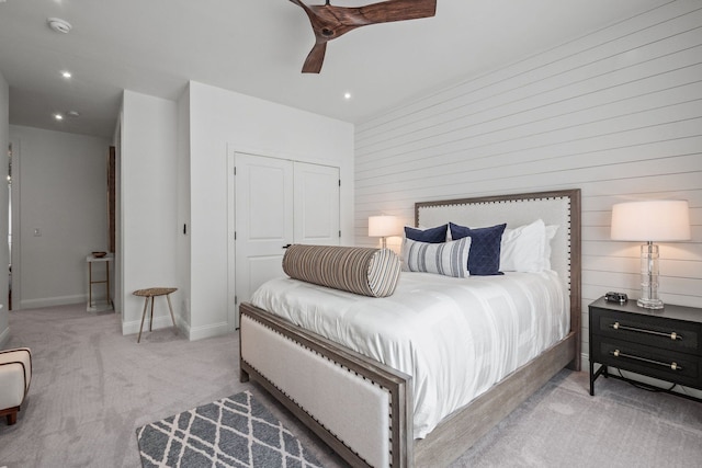 bedroom featuring ceiling fan, recessed lighting, light colored carpet, baseboards, and a closet