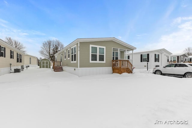 manufactured / mobile home with central air condition unit and a storage shed