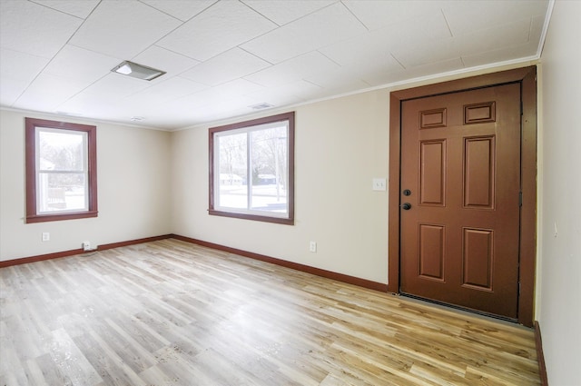 spare room with light wood-type flooring, crown molding, and baseboards