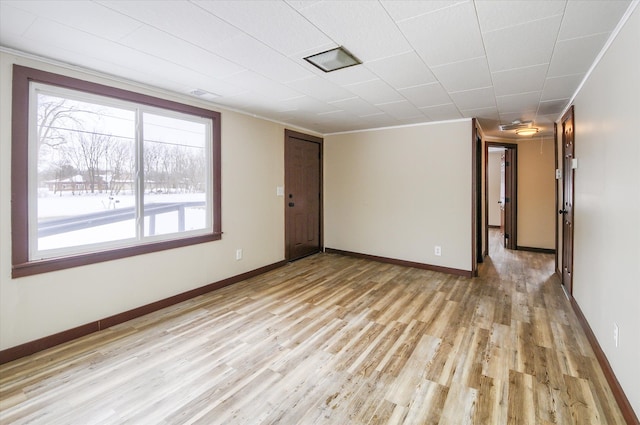 unfurnished room featuring ornamental molding, light wood finished floors, and baseboards