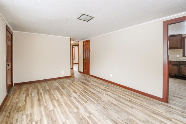 unfurnished room with light wood-type flooring, baseboards, and ornamental molding