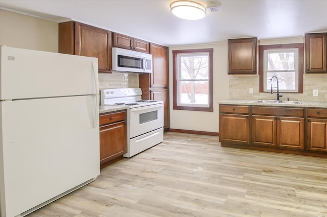 kitchen featuring light wood-style floors, white appliances, a healthy amount of sunlight, and a sink