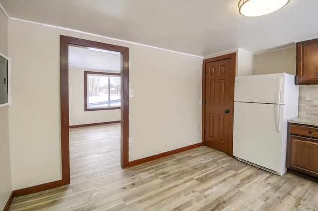 kitchen with light wood finished floors, backsplash, freestanding refrigerator, and baseboards