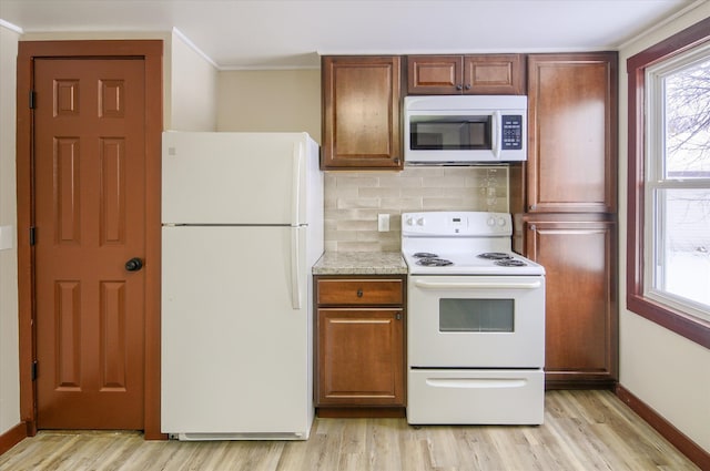 kitchen featuring white appliances, baseboards, decorative backsplash, ornamental molding, and light wood-type flooring