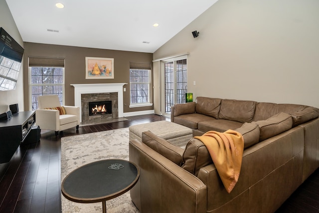 living area with dark wood-type flooring, a wealth of natural light, visible vents, and a fireplace