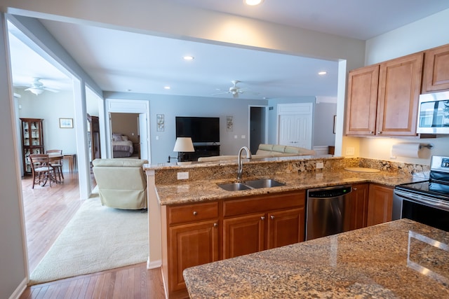 kitchen featuring a peninsula, stainless steel appliances, a sink, and open floor plan