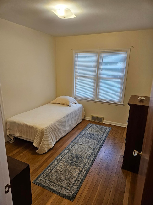 bedroom featuring dark wood finished floors, visible vents, and baseboards