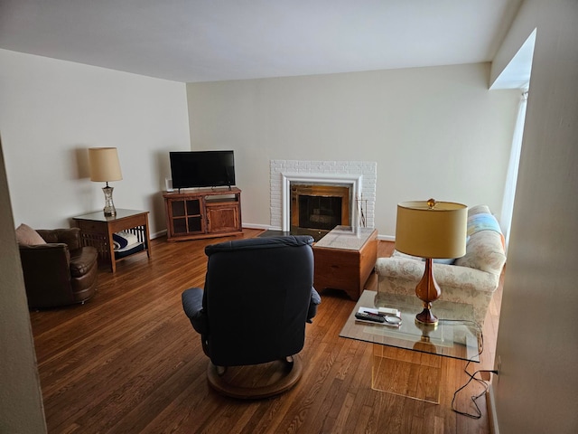 living area featuring dark wood-style flooring, a fireplace, and baseboards